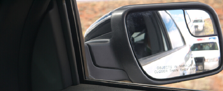Side view mirror of a car being pulled over for an unregistered vehicle infraction