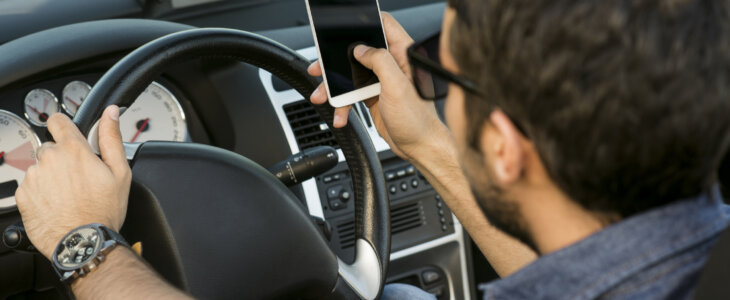 man typing text message on the phone in a convertible car